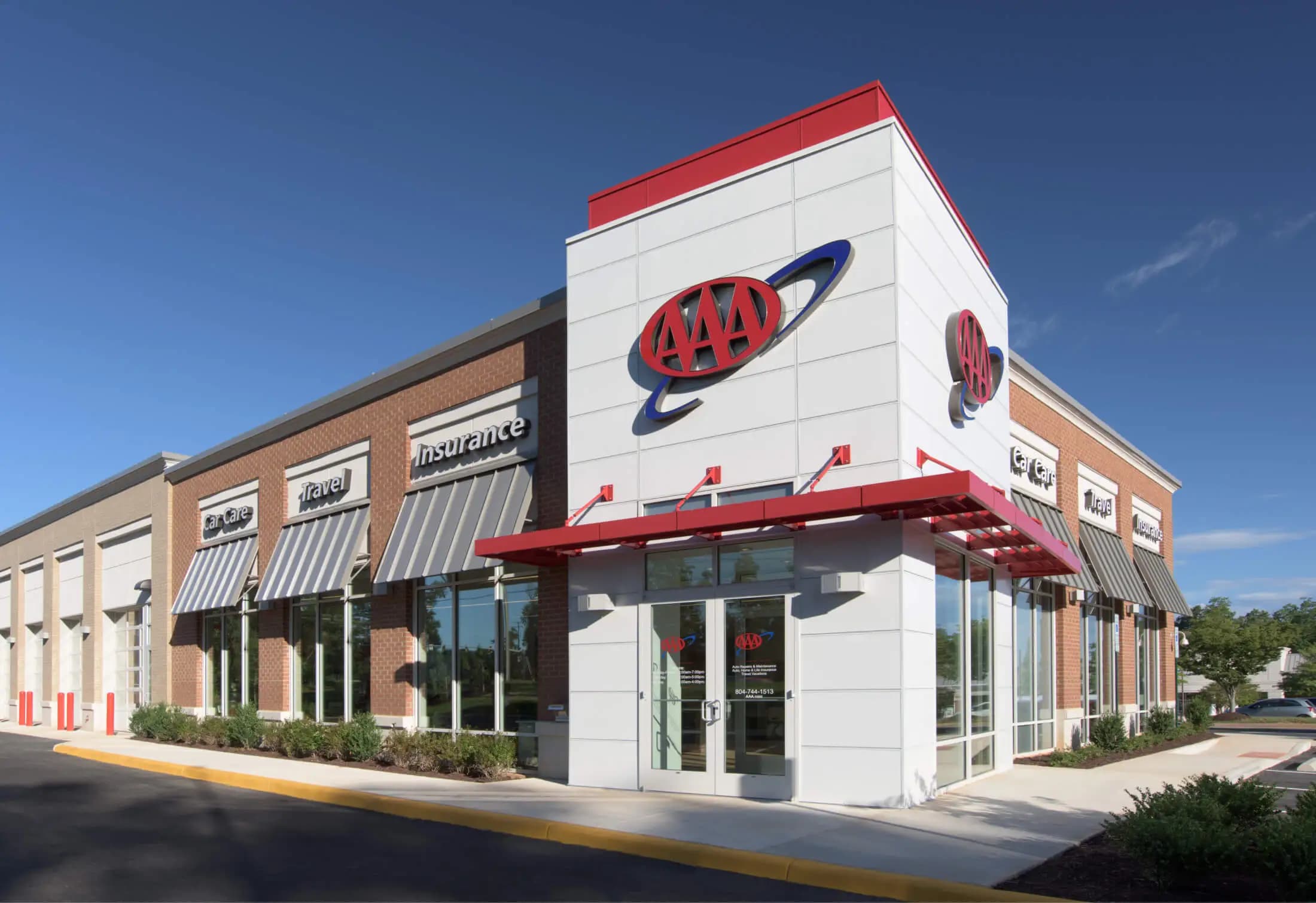 Exterior view of an AAA Service Center with signage for car care, travel, and insurance services under a clear blue sky.